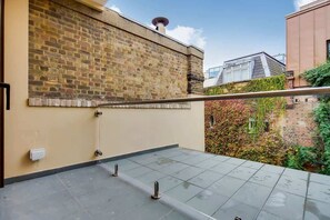 A rooftop terrace with a brick wall, a metal railing, and a clear view of the surrounding buildings. - BR13 - Elegant 1-Bed near London Bridge (Greater London)