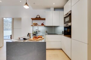 A modern kitchen with white cabinetry, a central island, and a built-in oven. - BR13 - Elegant 1-Bed near London Bridge (Greater London)