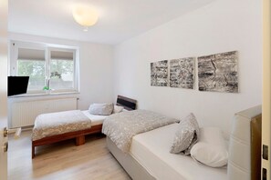 A bedroom with two beds, a window, and wall art.
