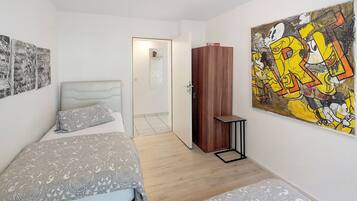 Ein Schlafzimmer mit einem Bett, einem Kleiderschrank, einem Bild und einer Tür zu einem anderen Raum.