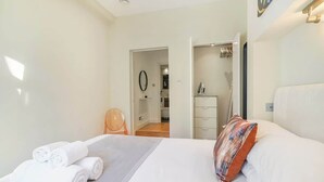 Ein Hotelzimmer mit einem Bett, einem Sessel, einem Schminktisch und einem durch eine geöffnete Tür einsehbaren Badezimmer.