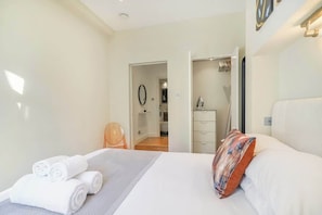 Ein Hotelzimmer mit einem Bett, einem Sessel, einem Schminktisch und einem durch eine geöffnete Tür einsehbaren Badezimmer.