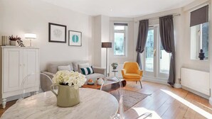 Ein modernes Wohnzimmer mit Sofa, Sessel, Esstisch und Kunstwerken an den Wänden.