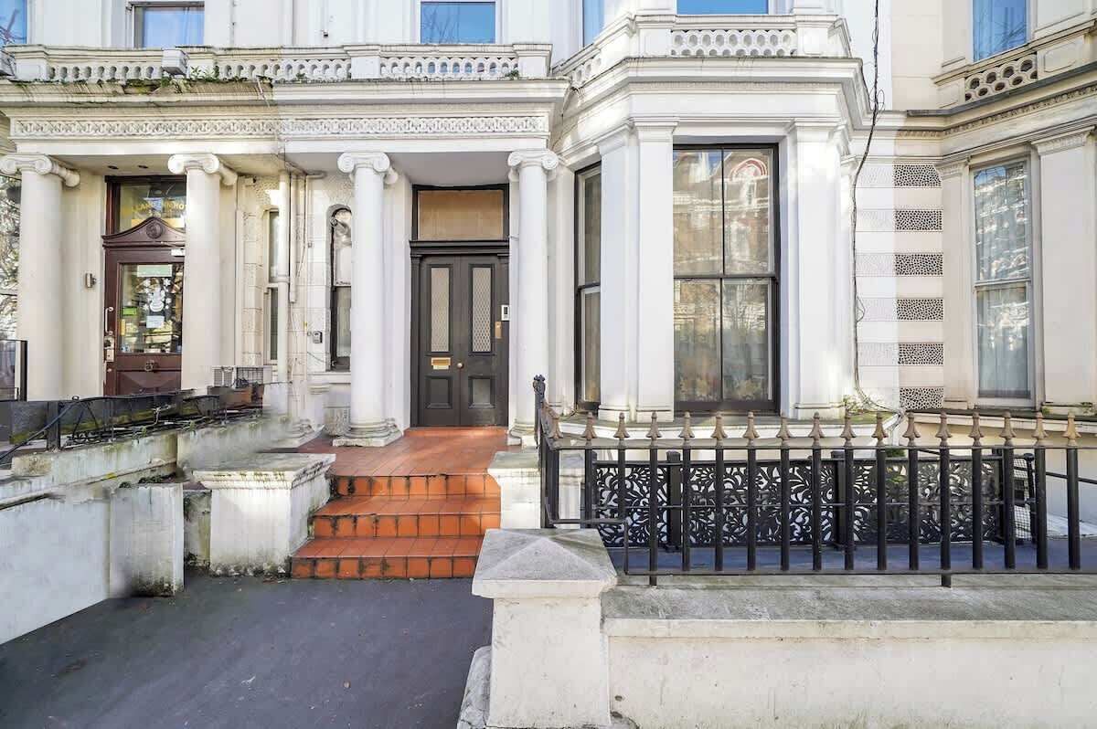 Un edificio clásico con entrada principal, columnas y una verja de hierro negro.