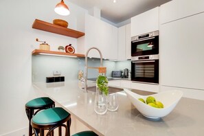 A modern kitchen with a central island, stainless steel appliances, and a minimalist design. - BR11 - Contemporary 2-Bed with City Vibes (Greater London)