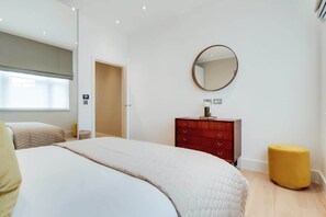 Ein Schlafzimmer mit Bett, Schminktisch, Spiegel und Fenster.