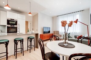 A modern kitchen with a built-in oven and a dining area with a round table and bar stools. - BR11 - Contemporary 2-Bed with City Vibes (Greater London)