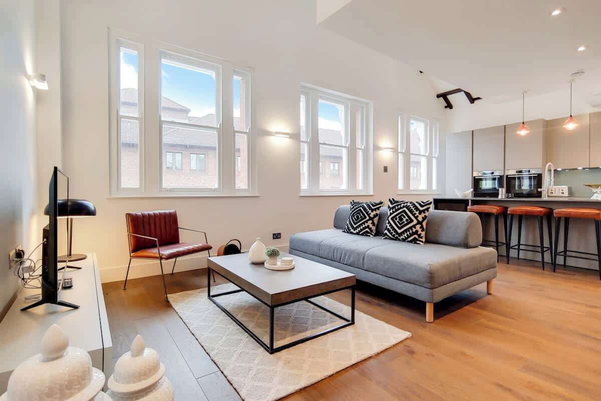 A modern living room with a sofa, coffee table, and a dining area with bar stools.