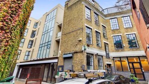 Un edificio de varios pisos con fachada de ladrillo, ventanas grandes y techo plano.