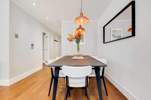 A dining area with a table, chairs, a pendant light, and a vase with flowers. - BR12 - Modern & Stylish 2-Bed Apartment in Borough (Greater London)