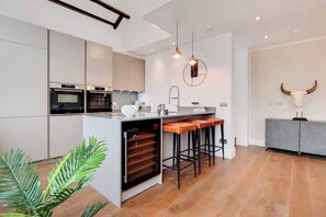 A modern kitchen with a central island, bar stools, and a large horn sculpture. - BR12 - Modern & Stylish 2-Bed Apartment in Borough (Greater London)