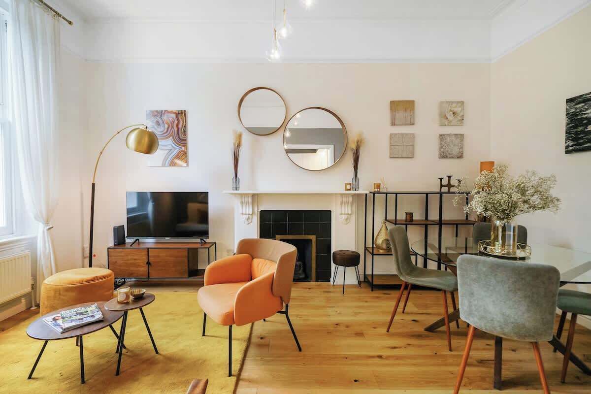 Un salon moderne doté d’une cheminée, d’un téléviseur et d’un coin repas avec des chaises et une table.