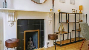 A living room with a fireplace, a round mirror, a black tiled wall, and a modern shelving unit. - LG4 - Modern & Spacious 2-Bed in Notting Hill (Greater London)