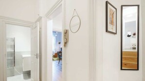 A hallway with a white door, a round mirror, and a framed picture on the wall. - LG4 - Modern & Spacious 2-Bed in Notting Hill (Greater London)