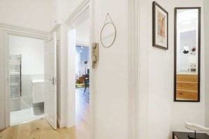 Ein Flur mit einer weißen Tür, einem runden Spiegel und einem gerahmten Bild an der Wand.