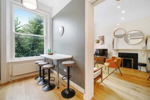 Eine moderne Küche mit Essbereich, ein großes Fenster mit Blick auf Bäume und ein Kamin.