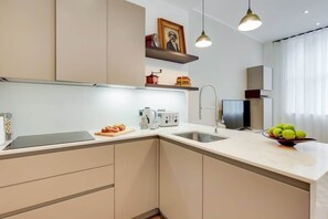 Una cucina moderna con forno integrato, lavello e un piano di lavoro con una ciotola di frutta.