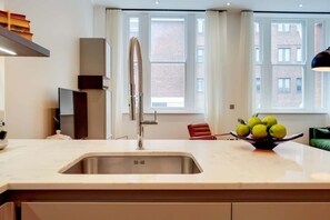 Una cucina moderna con lavello in acciaio inossidabile, forno integrato e finestra con tende.