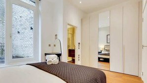 Ein Schlafzimmer mit Bett, Fenster, Spiegel und Kleiderschrank.