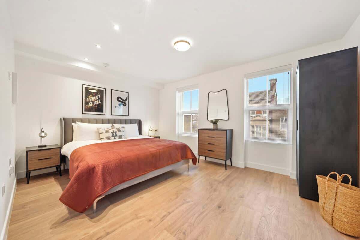 A bedroom with a bed, bedside tables, a dresser, a mirror, and a window.