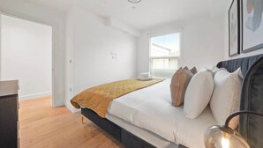 Une chambre à coucher avec un lit, une table de chevet, une fenêtre et une porte.