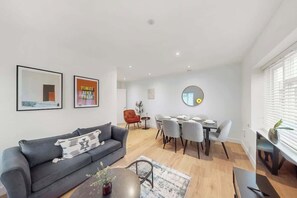 Een moderne woonkamer met een grijze bank, eettafel en stoelen.