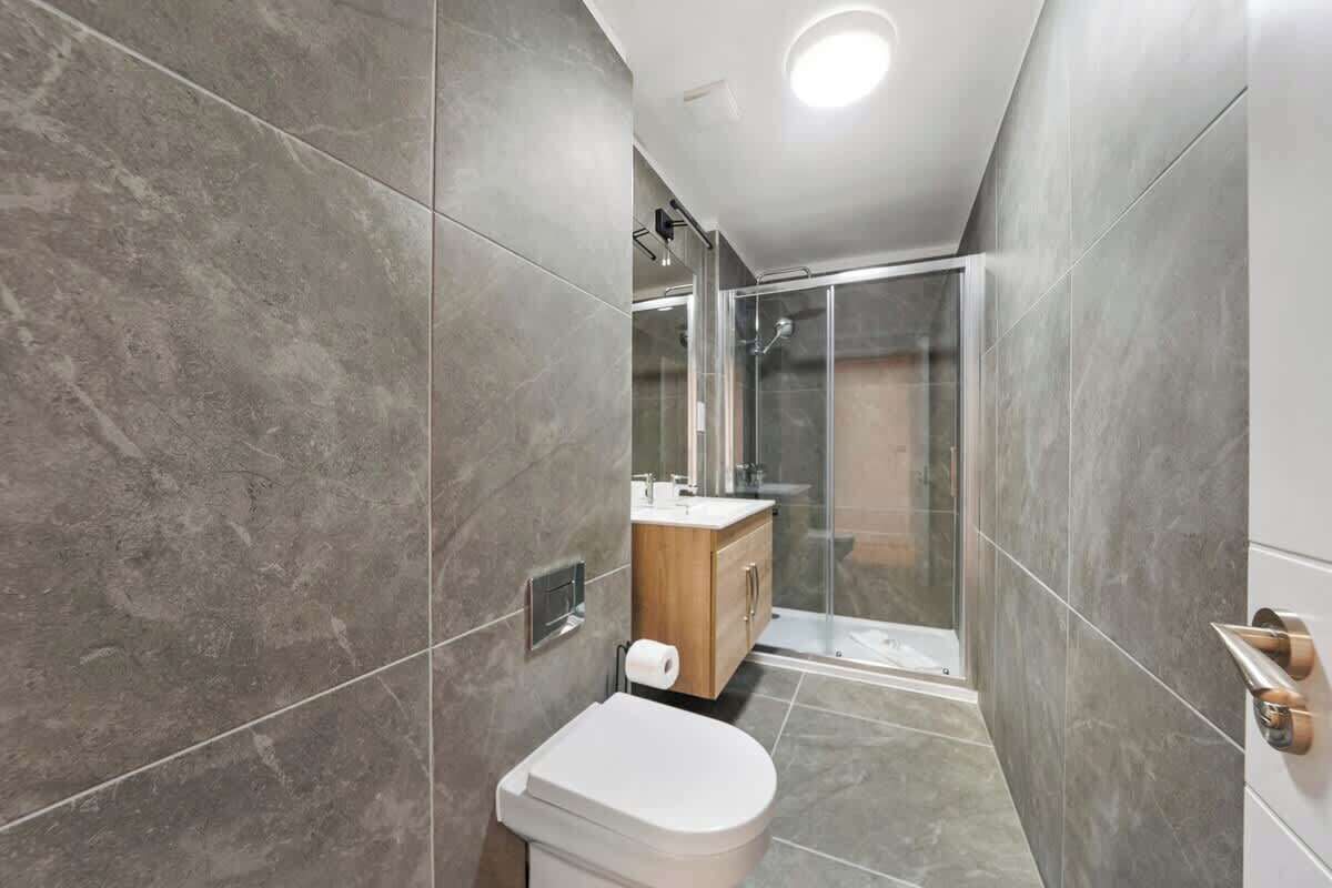 Un baño moderno con inodoro, ducha y cabina de ducha con mampara de vidrio.