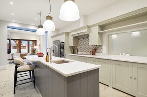 A modern kitchen with a central island, pendant lights, and a view to the outside. - MUR1 - Modern and Stylish 6-bed House in Wimbledon (London)
