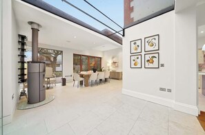 A modern interior with a dining area, a fireplace, and artwork on the walls. - MUR1 - Modern and Stylish 6-bed House in Wimbledon (London)
