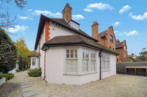 A two-story house with a white facade, a brick chimney, and a gravel driveway. - MUR1 - Modern and Stylish 6-bed House in Wimbledon (London)