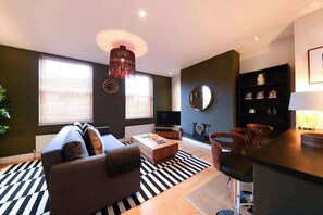 Ein modernes Wohnzimmer mit einer Couch, einem Couchtisch, einem Fernseher und einem Essbereich mit Stühlen.