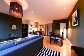 Ein modernes Wohnzimmer mit Sofa, Esstisch und Küchenzeile.