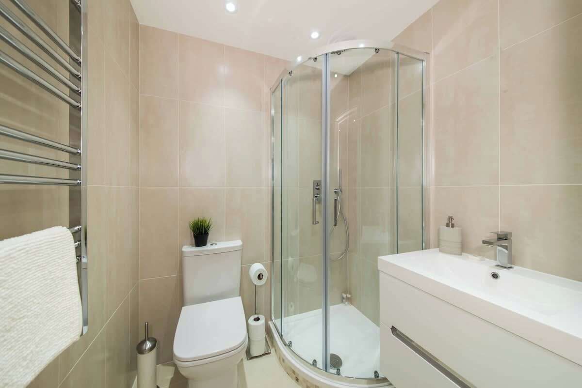 A modern bathroom with a glass-enclosed shower, a white toilet, and a white sink with a mirror.