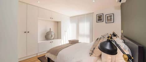 Une chambre à coucher avec un lit, une lampe de chevet et une étagère ornée d’objets décoratifs.