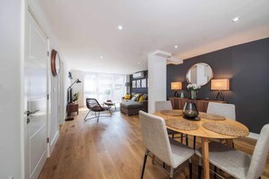 A modern living room with a dining area, a sofa, and a coffee table. - BR7 - Modern 2-Bed Apartment with Private Terrace (Greater London)