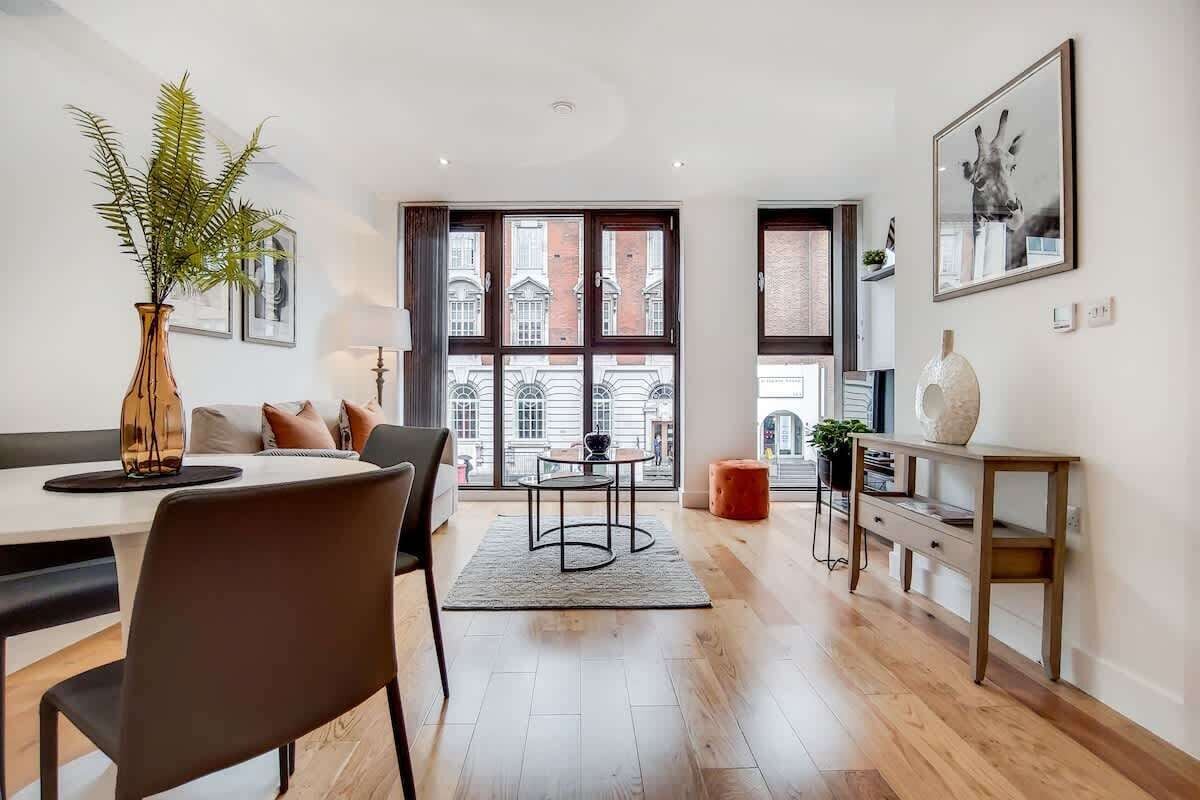 A modern dining area with a table, chairs, and a vase of plants.