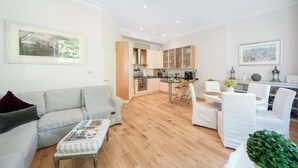 Un salon moderne comprenant un canapé, un pouf et un coin repas avec des chaises et une table.