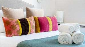 Un lit bien fait, avec des oreillers, une lampe de chevet et des serviettes pliées.