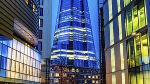 Un rascacielos moderno con una punta distintiva y afilada, rodeado de otros edificios altos.