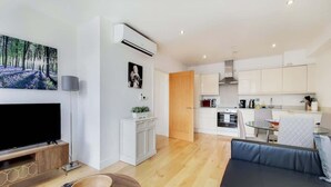 Una sala de estar moderna con un televisor de pantalla plana, un cuenco de madera y un control remoto en el suelo.