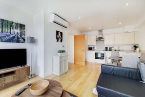 A modern living room with a flat-screen TV, a wooden bowl, and a remote on the floor. - BR6 - Beautiful 1 Bed Flat in Heart of Borough (Greater London)