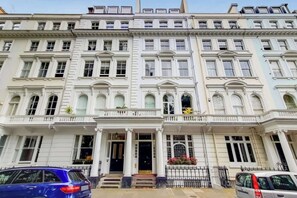 A multi-story building with a symmetrical facade, large windows, and a central entrance with steps. - CWG1 - Elegant 3-Bed on Kensington Garden Square (London)