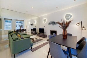 Ein modernes Wohnzimmer mit einer Couch, einem Esstisch und einem Fernseher.