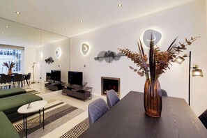 Una sala de estar moderna con chimenea, comedor y un amplio ventanal.