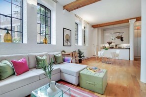 Un salon moderne avec un canapé, un pouf et une table basse en verre.