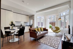 A modern living space with a dining area, sofa, and a TV. - DG1 – Family-Friendly 2-Bed with Garden in Acton (Greater London)