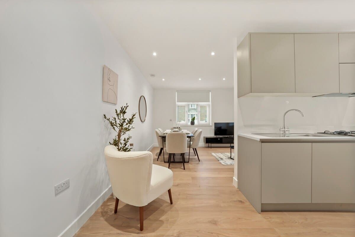 A modern kitchen with a built-in island, a dining area with a table and chairs, and a living room with a sofa and a TV.