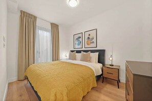 Ein Hotelzimmer mit Bett, Nachttischen, einem Schminktisch und Bildern an der Wand.