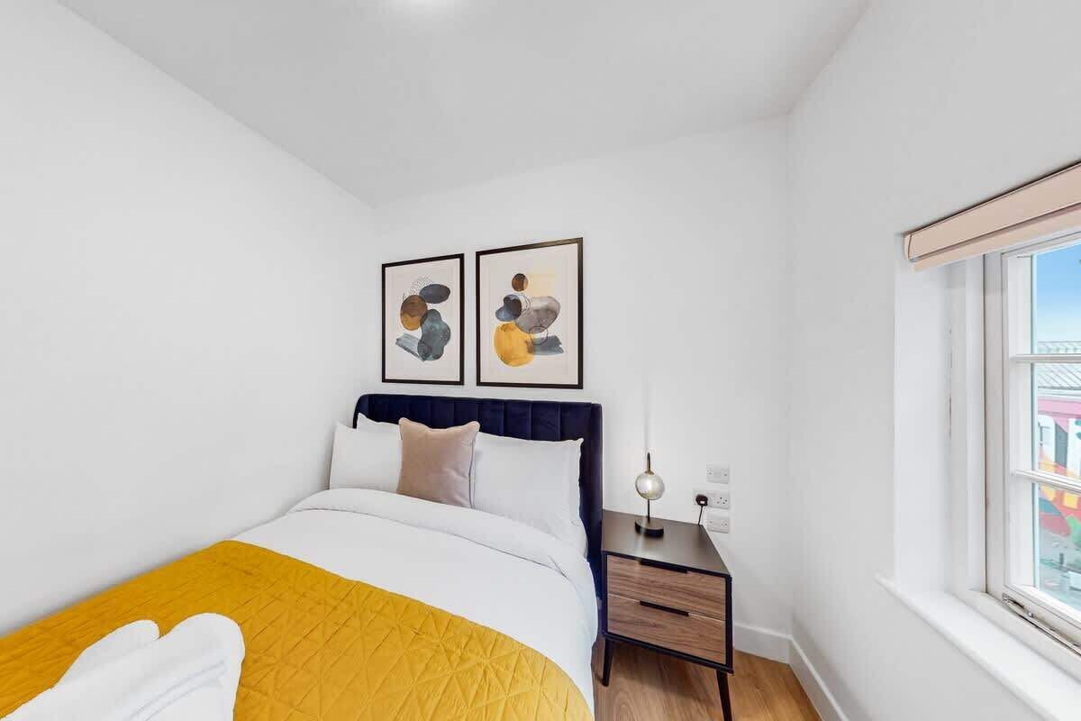 A hotel room with a bed, a bedside table, a nightstand, and a window.