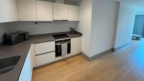 A modern kitchen with white cabinets, a black countertop, a built-in oven, and a microwave. - The Zenith Residence - 2 Bedroom (London)